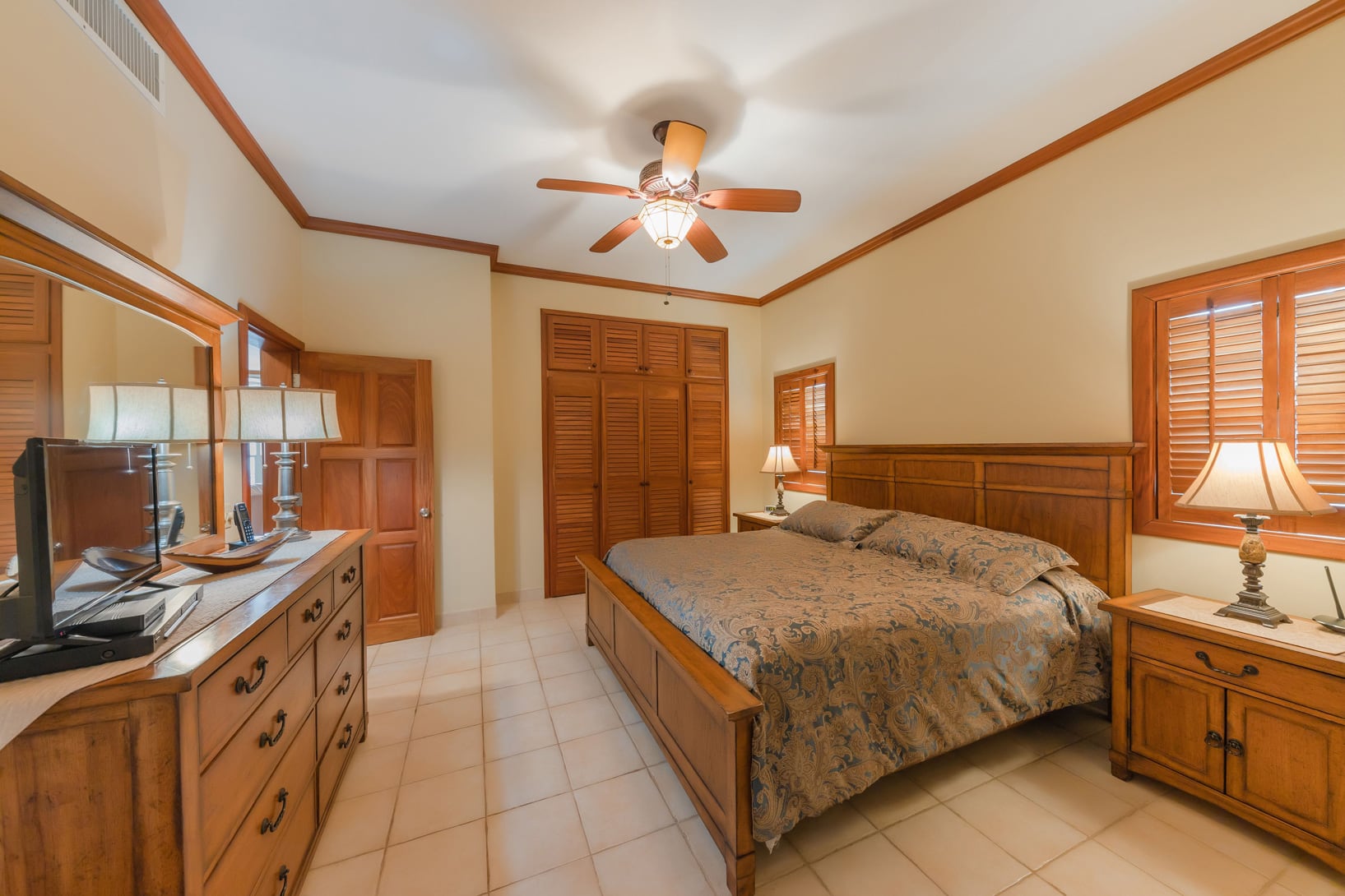 Warm and inviting master bedroom with a comfortable king-size bed, tropical accents, and a cozy atmosphere